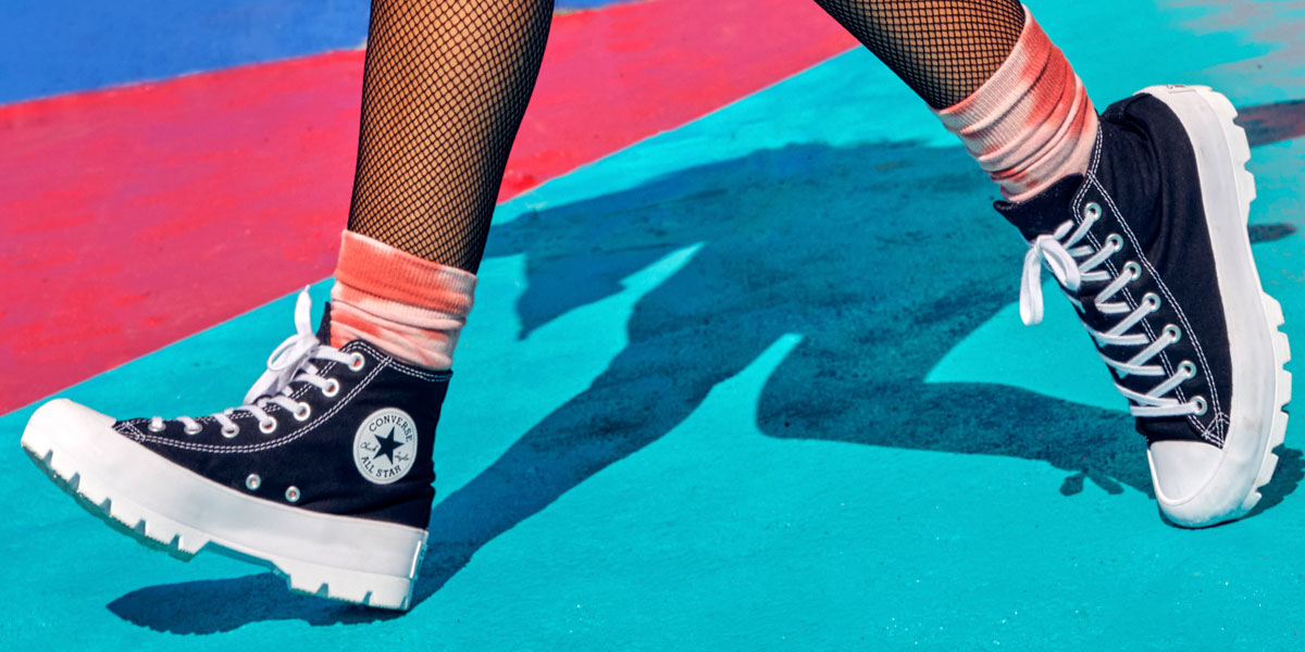 Woman walking with Converse high-tops across a colorful painted floor.